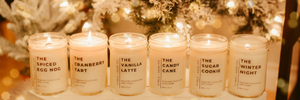 6 candles in mason jars with a christmas tree behind them