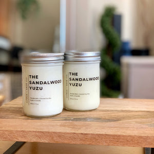 2 coconut soy candles on wooden platform with blurred background