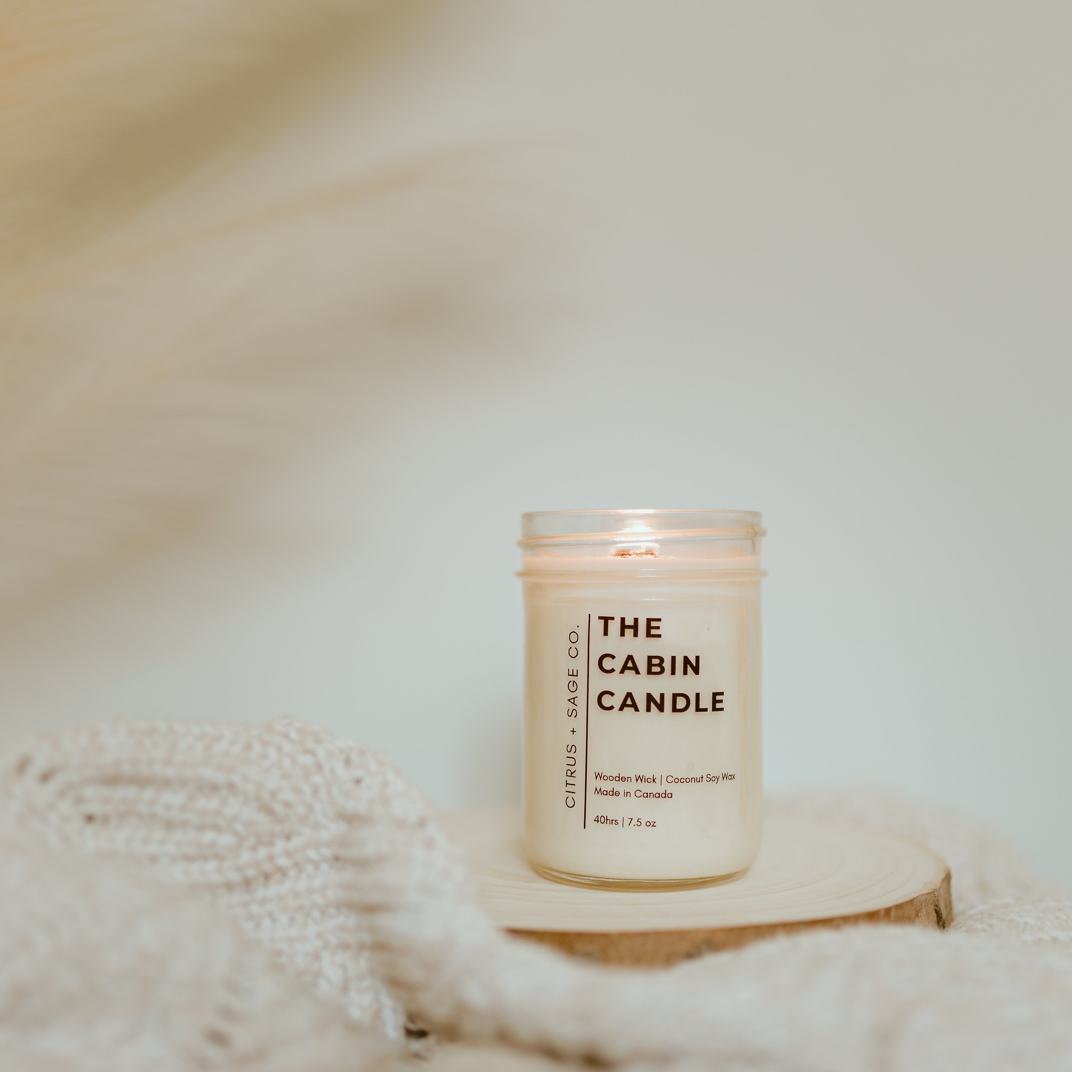 candle on wooden disc with feathers in background
