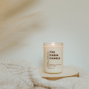 candle on wooden disc with feathers in background