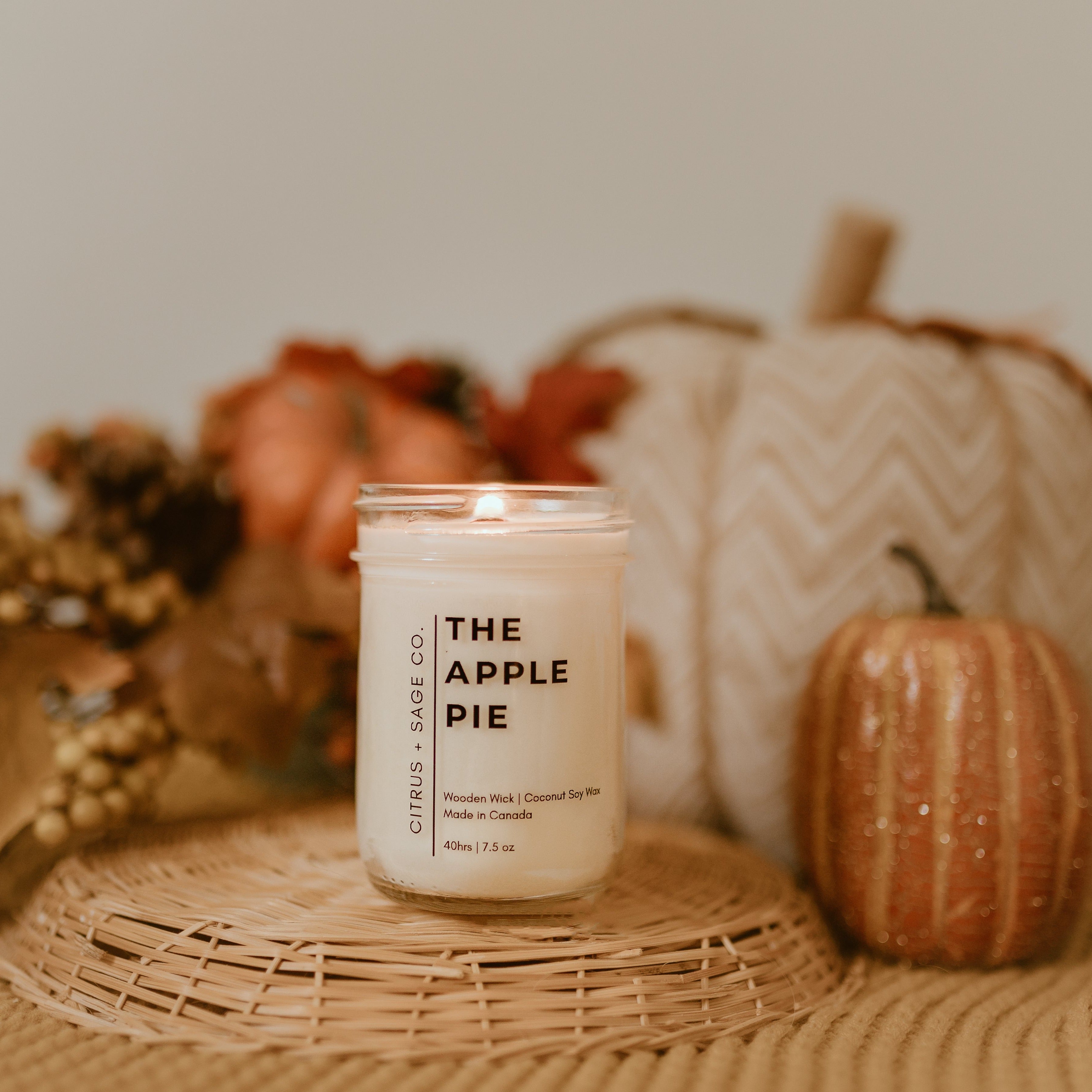candle on wicker basket with pumpkins in background