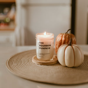 candle on table with 2 pumpkins to the right