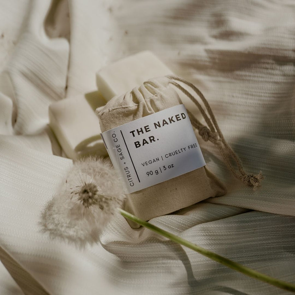 bar soap in cotton bag on top of beige sheet with dandelions